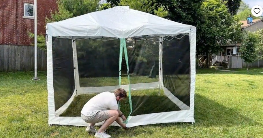 man setting up ozark trail screen tent in backyard