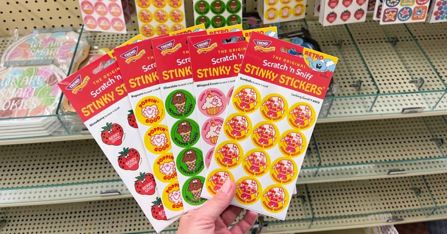 Person holding up retro stinky sticker packs inside Hobby lobby