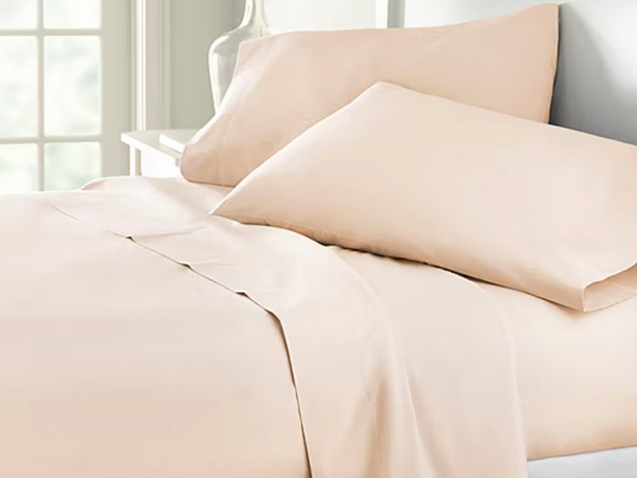 peach sheet set with pillows on bed 
