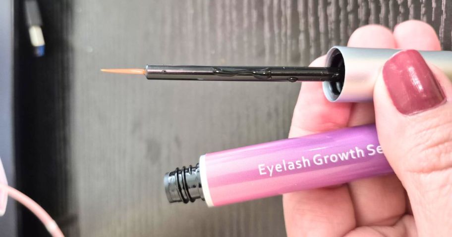 holding an open tube of eyelash serum