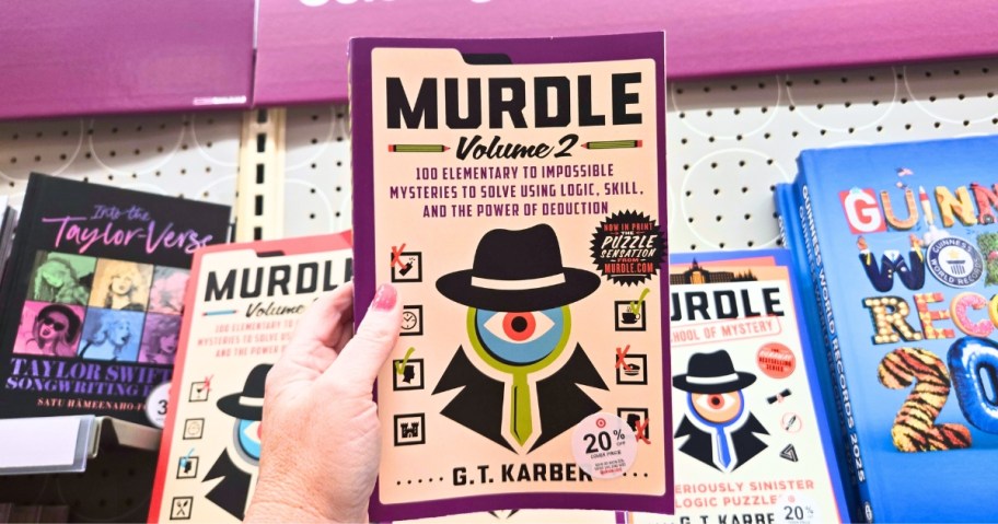 a womans hand holding a copy of murdle vol 2 