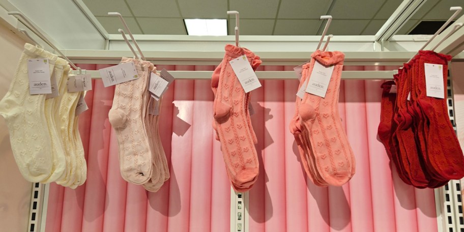 white, pink, and red socks hanging in store 