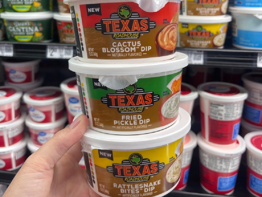 hand holding three new texas raod house dips at the store