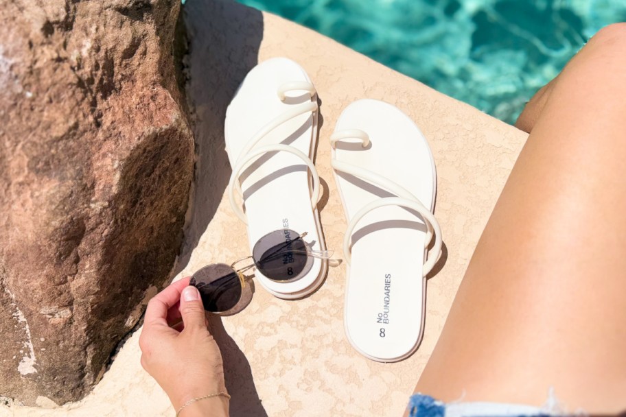 white toe loop sandals next to pool and sunglasses