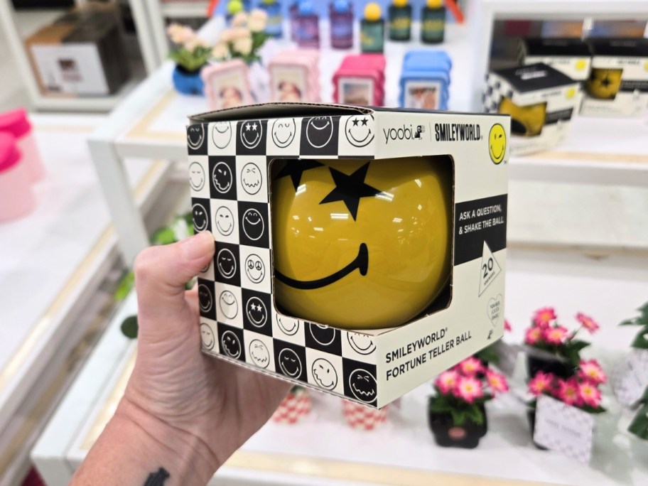 hand holding a yellow round smiley face fortune teller ball