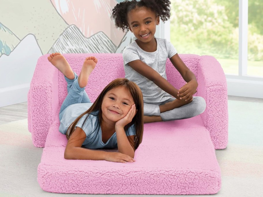 two girls laying on a pink sherpa convertible sofa