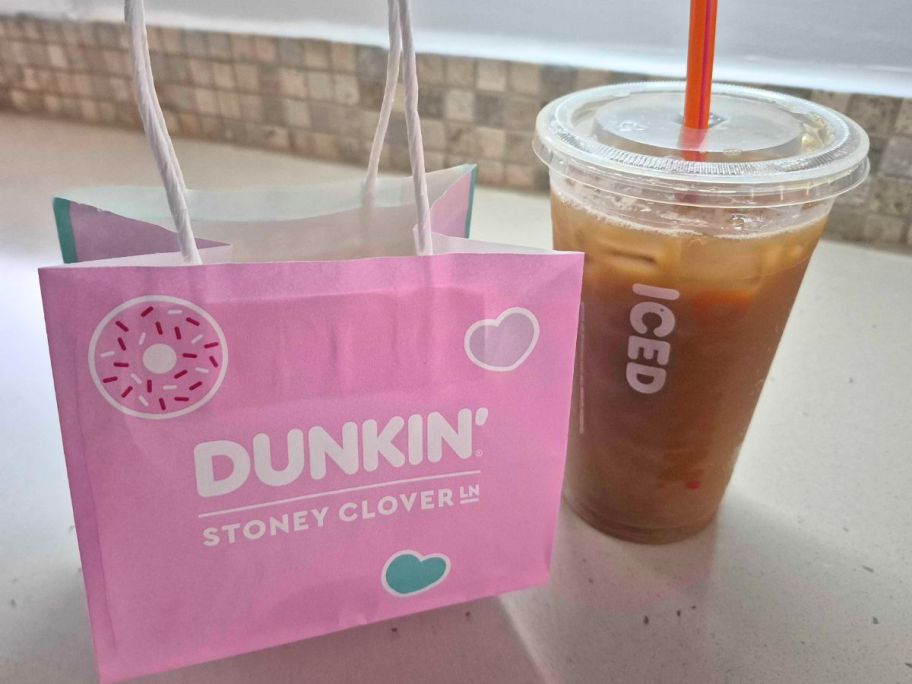 A Dunkin' Iced Coffee next to a pink Stoney Clover bag