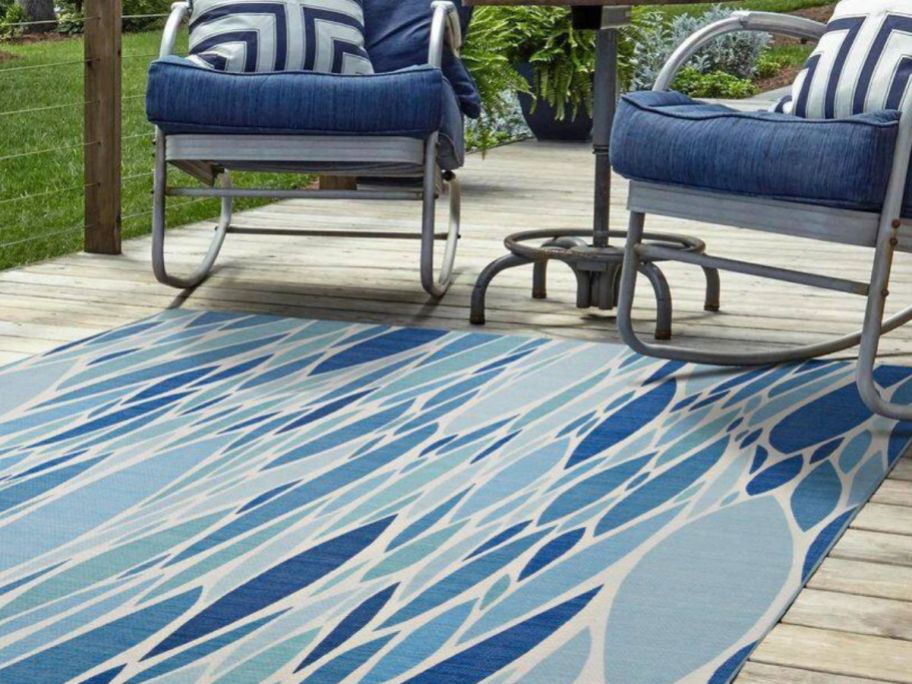 blue and ivory designed rug placed on a patio with two rocking chairs on it