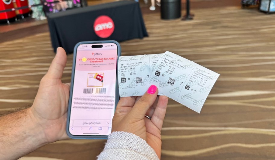 hand holding phone and two movie tickets