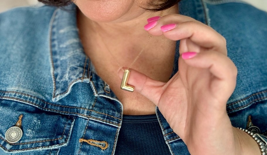 A woman wearing a gold bubble letter necklace