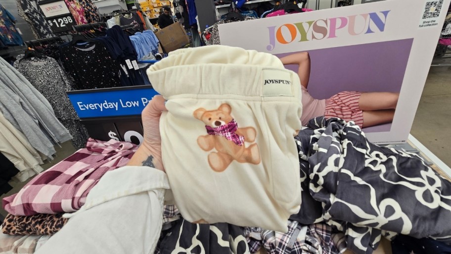 a womans hand a pair of folded pajama pants