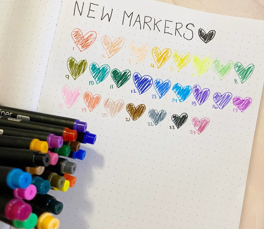 journaling pens by a notebook with hearts on it