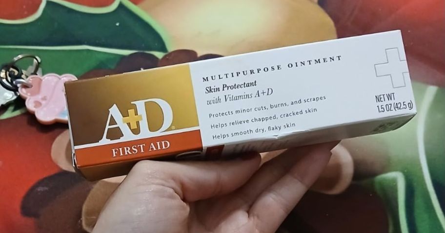 A person holding a box of A+D First Aid Ointment