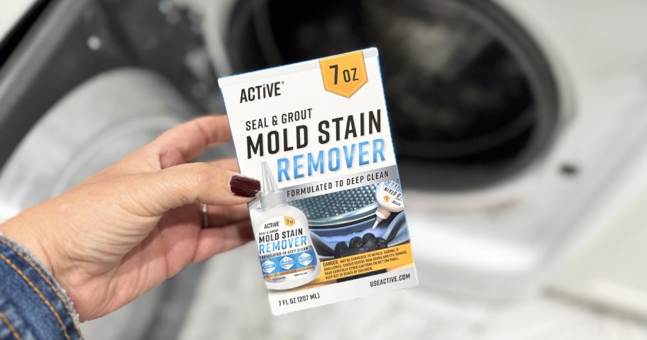 holding a box of Active Mold Stain Remover in front of washing machine