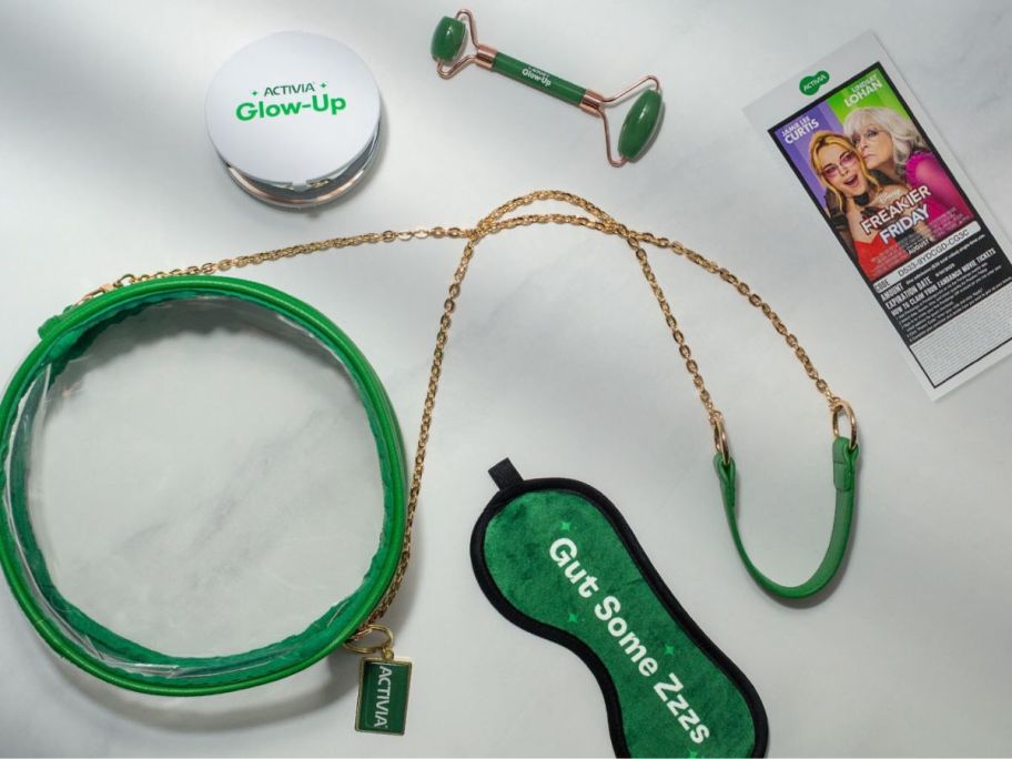 A green and clear purse, eye roller, and phone