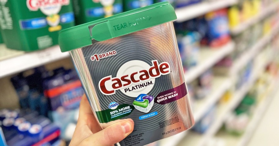 hand holding up a silver container of Cascade Platinum Dishwasher Pods in store