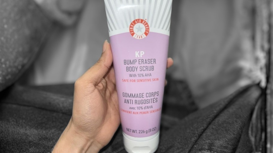 womans hand holding a tube of bump eraser body scrub