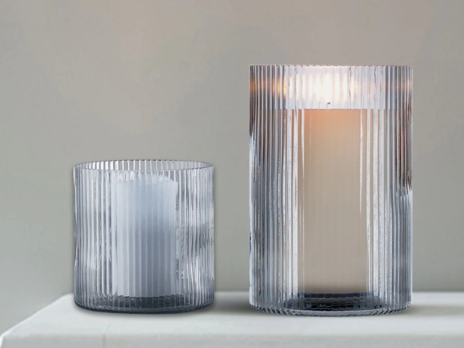 2 blue glass ribbed candle holders in different sizes on a mantle