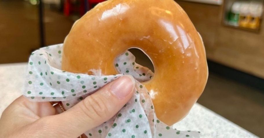 Hand holding a Krispy Kreme Glazed Doughnut