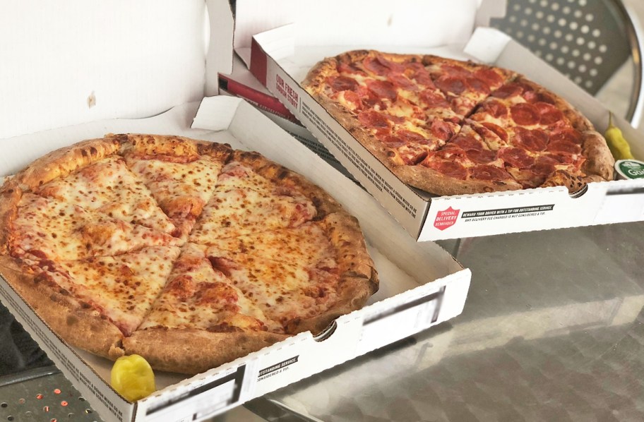 two opened pizza boxes with cheese and pepperoni pizzas
