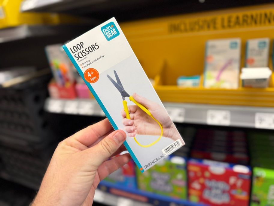 A person holding a white box with loop scissors inside in a store