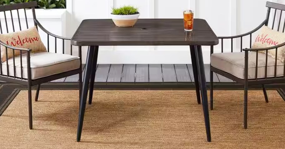 brown square outdoor table with chairs on either side