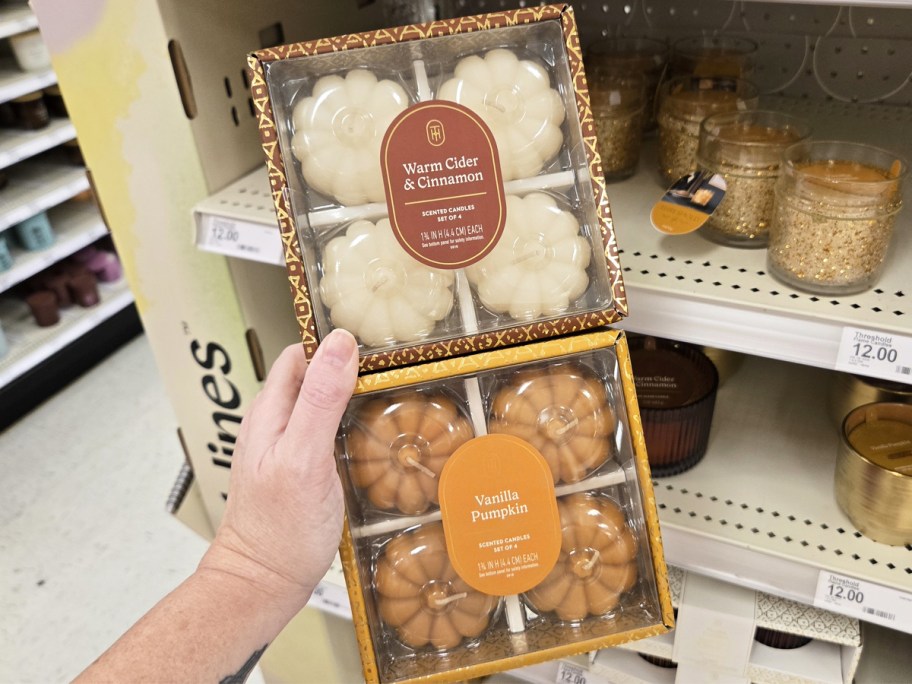 hand holding boxed sets of mini pumpkin candles