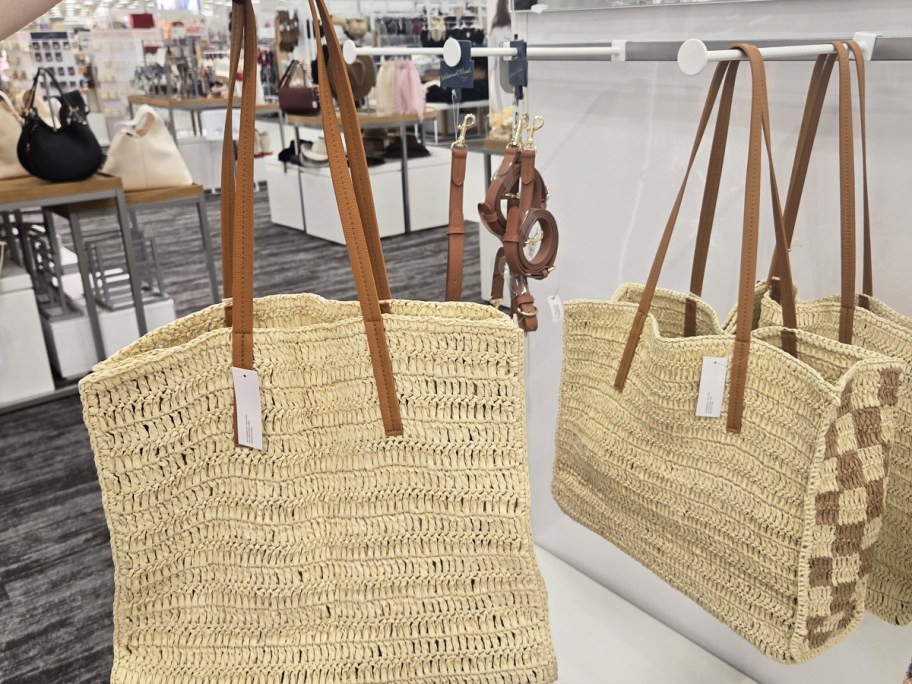 hand holding up a straw tote bag in store