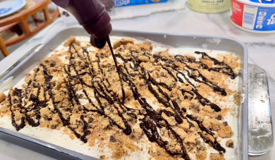 adding chocolate syrup to ice cream cake