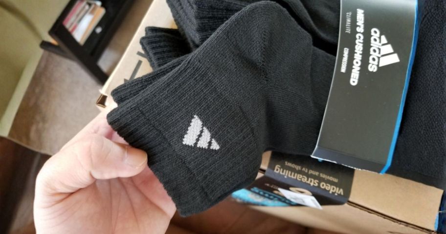 hand holding black adidas sock from package