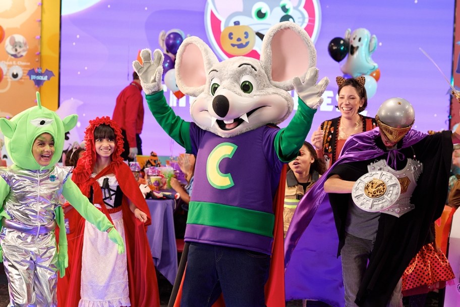 Chuck E cheese character in a vampire halloween costume interacting with costumed kids