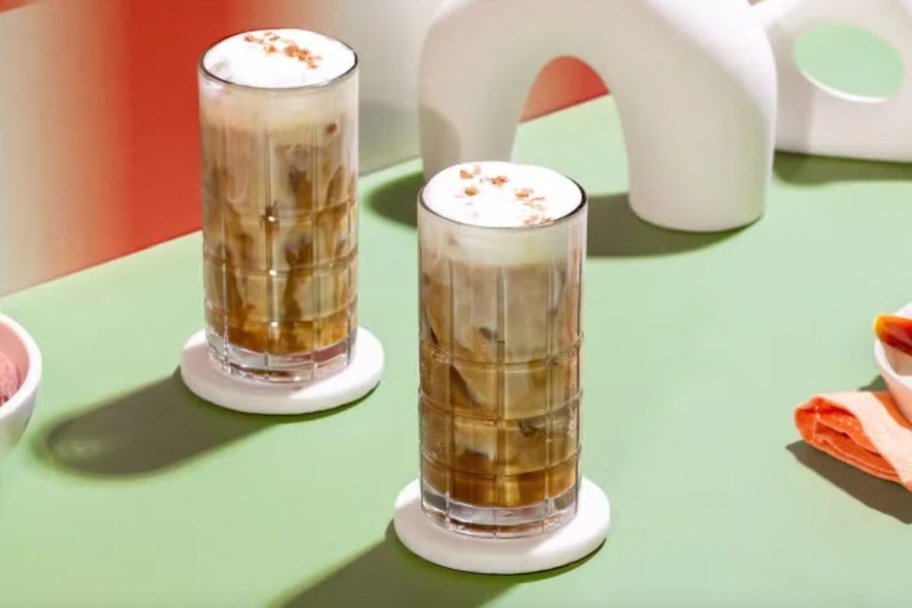 two iced coffee drinks on green table