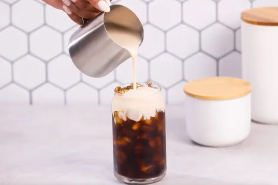 tin cup pouring over iced coffee