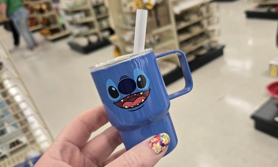 a womans hand holding a blue stitch mini tumbler