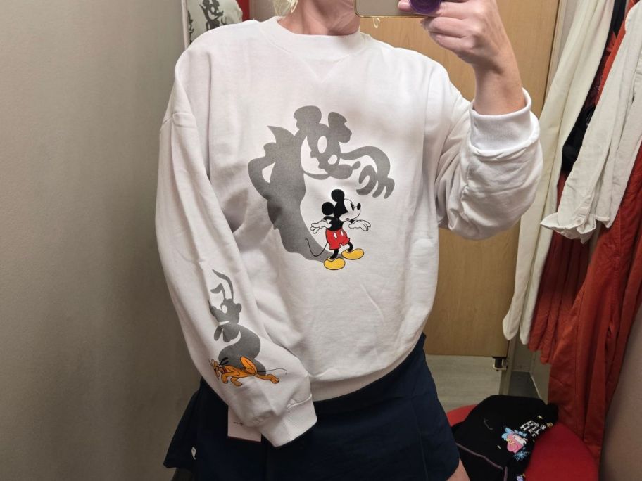 woman wearing white mickey halloween sweatshirt in dressing room in store