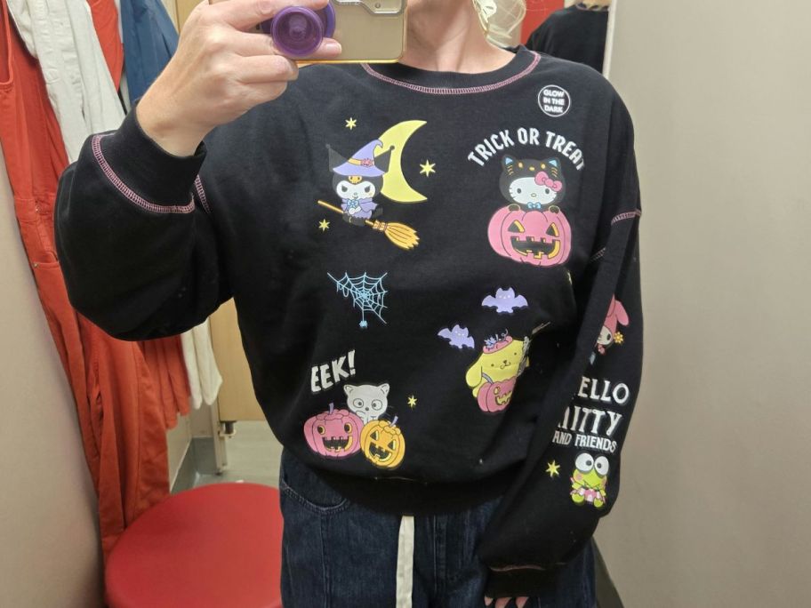 woman wearing black halloween hello kitty sweatshirt in dressing room in store