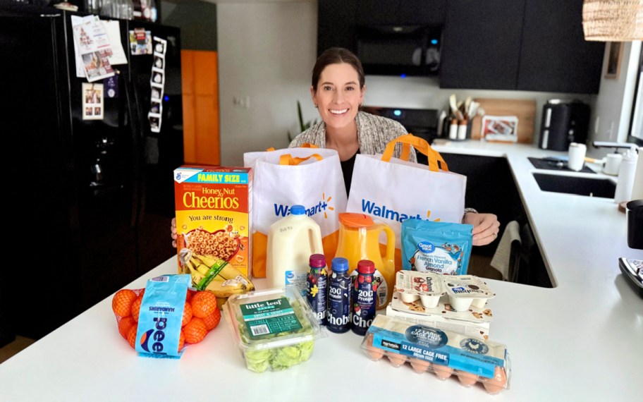smiling woman behind groceries and walmart delivery bags displayed on a counter