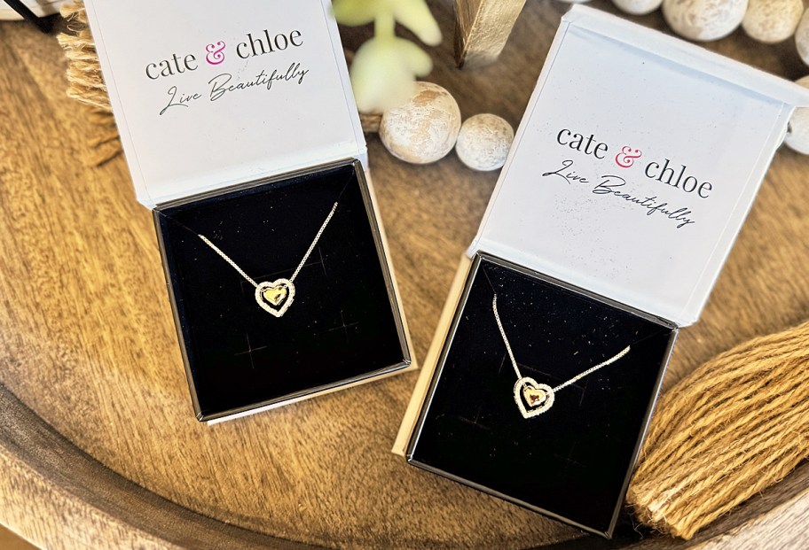 two opened jewelry boxes with matching heart necklaces inside