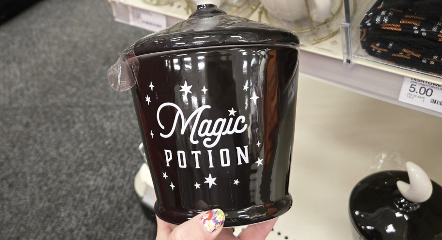 hand holding a black jar that says magic potion