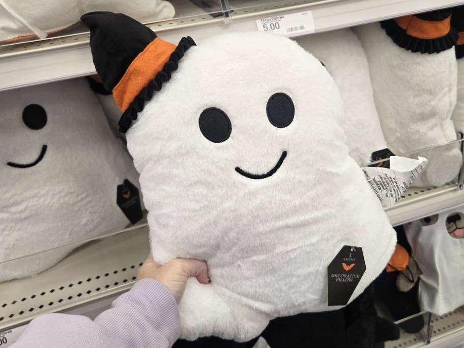 hand holding a ghost throw pillow wearing a witch hat
