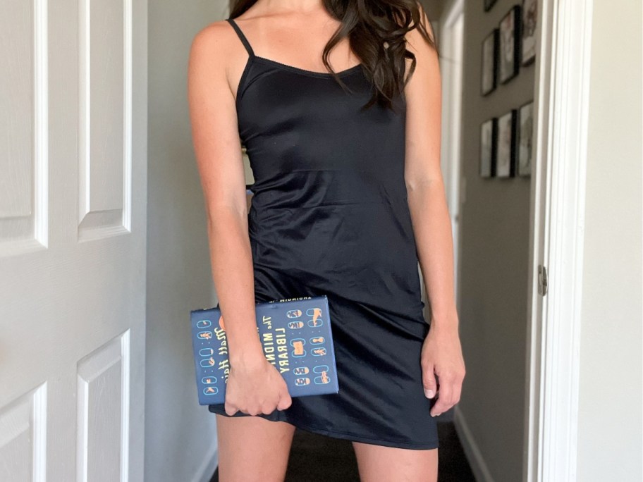 woman wearing a black full slip, holding a book