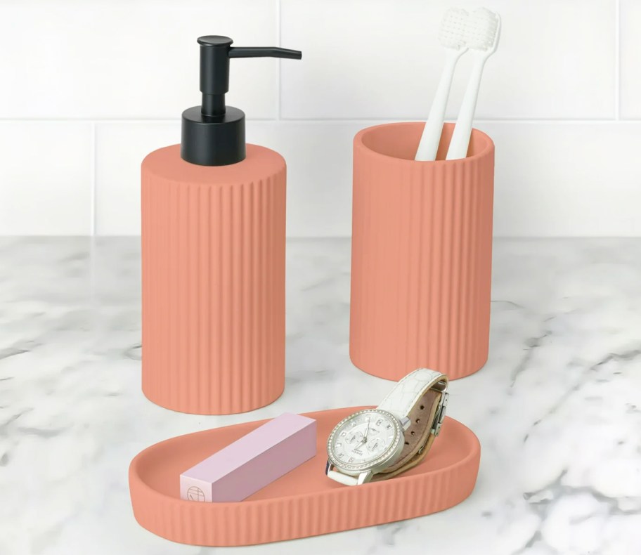 pink ribbed bathroom accessories set on counter