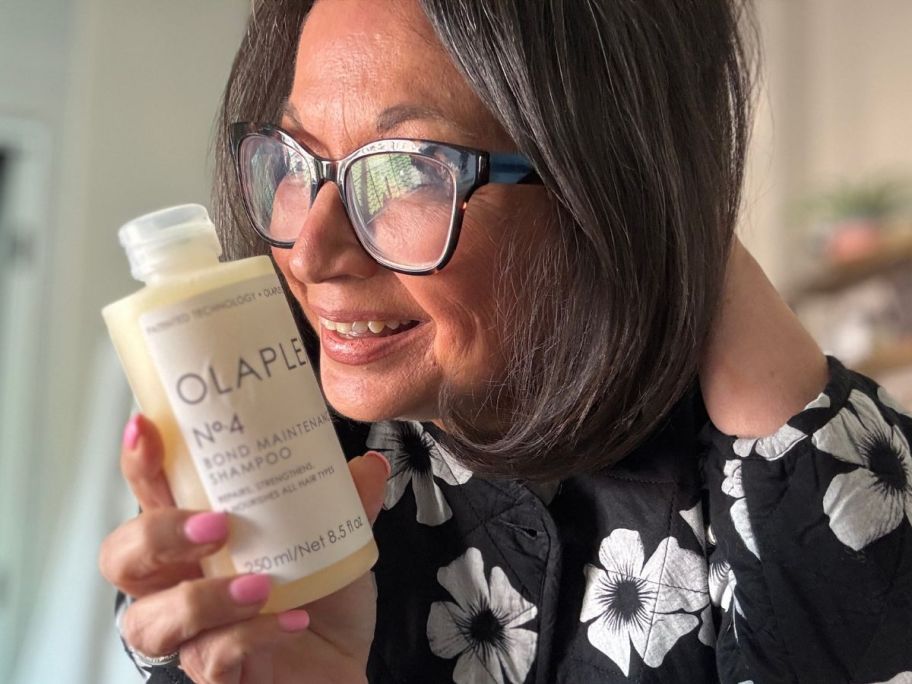 Woman holding a bottle of Olaplex next to her hair