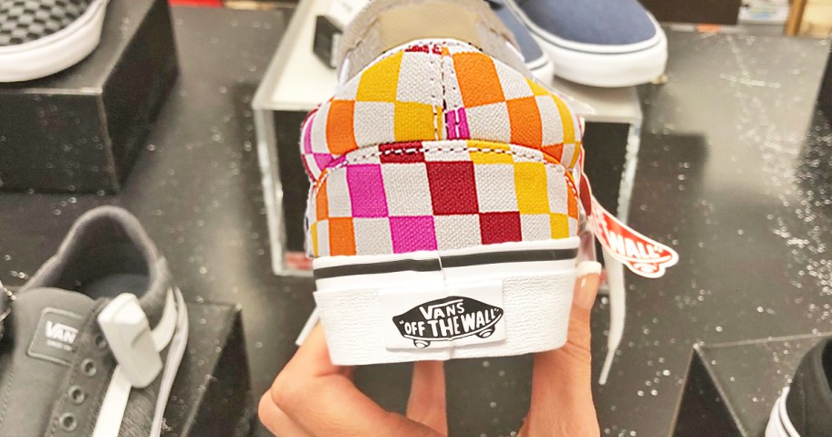 hand holding up a colorful checkerboard print sneaker