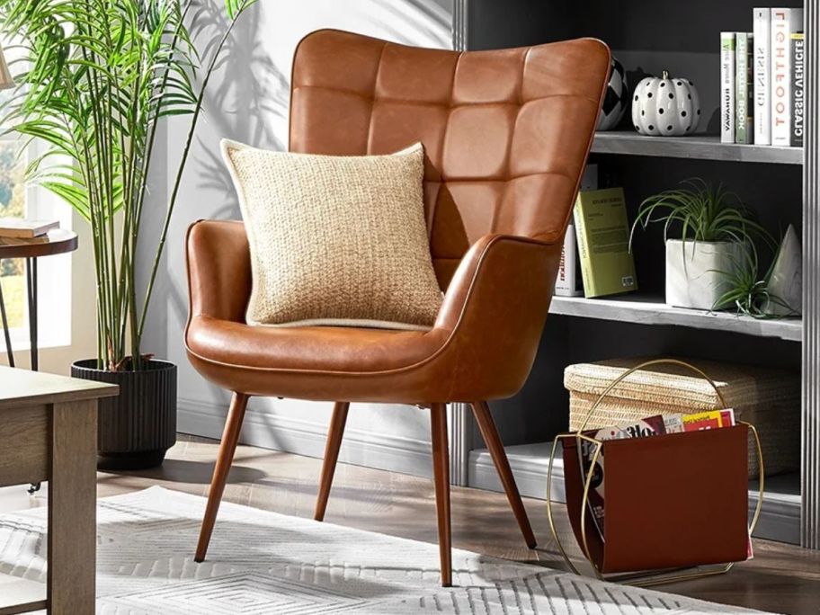 A Alden Design Mid-Century Modern Faux Leather Wingback Accent Chair with a throw pillow on it