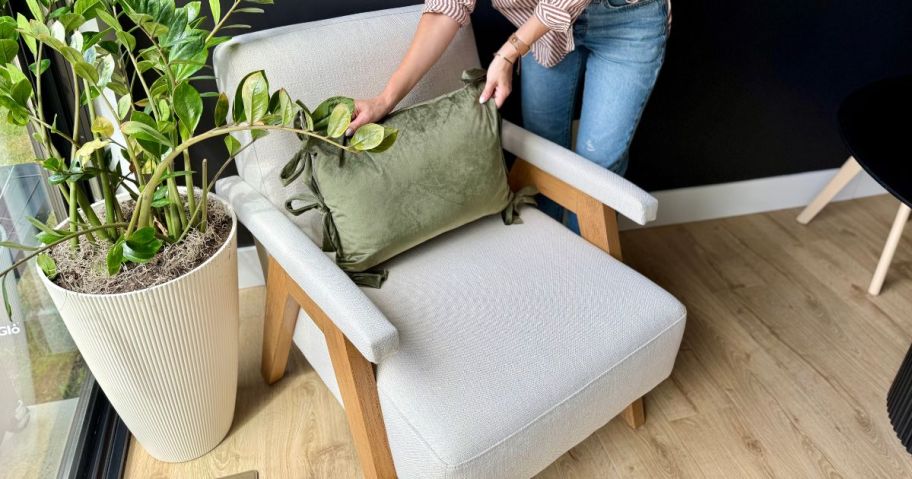 Woman straightening a pillow on a better homes & gardens chair