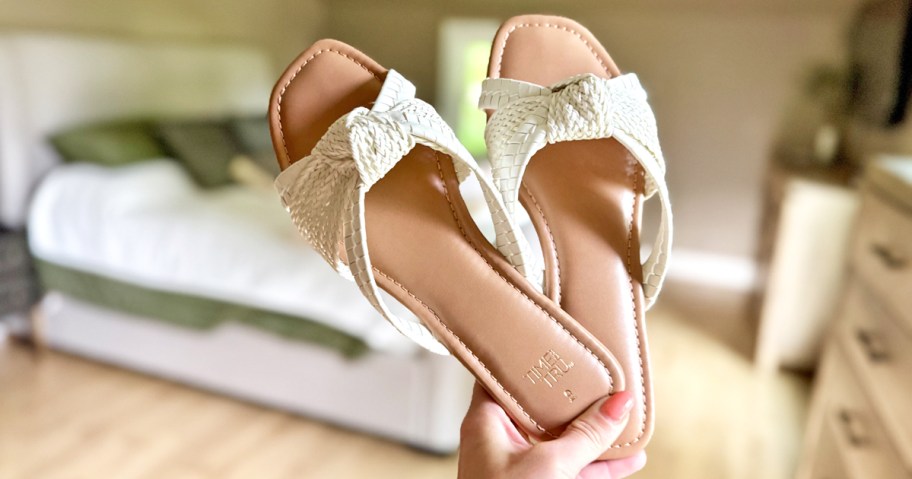 woman holding up a pair of knotted strap sandals