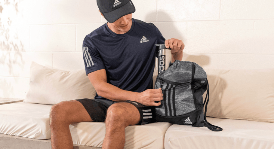 man pulling adidas stainless steel bottle out of sackpack
