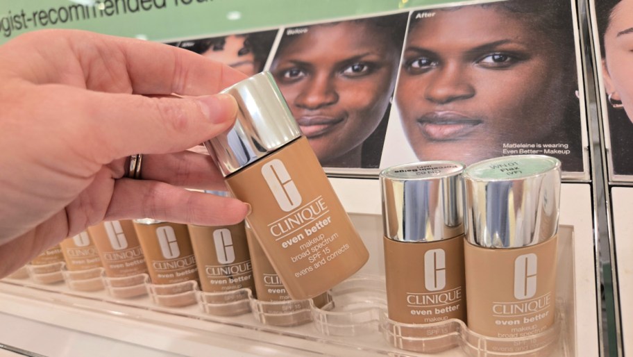 hand tipping a bottle of foundation off a shelf display