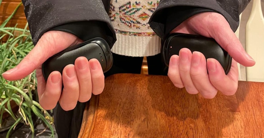 person holding two black hand warmers